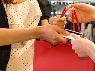 A person being given a red handbag in exchange for their credit card. 