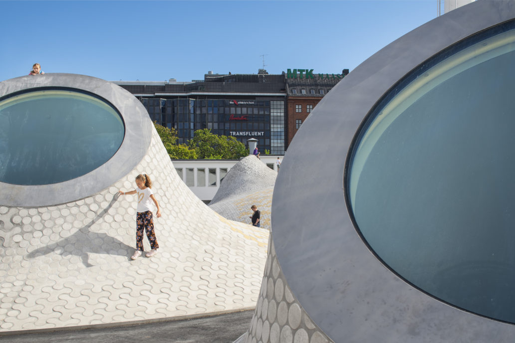 Children playing on peculiar brick shapes that have windows. 