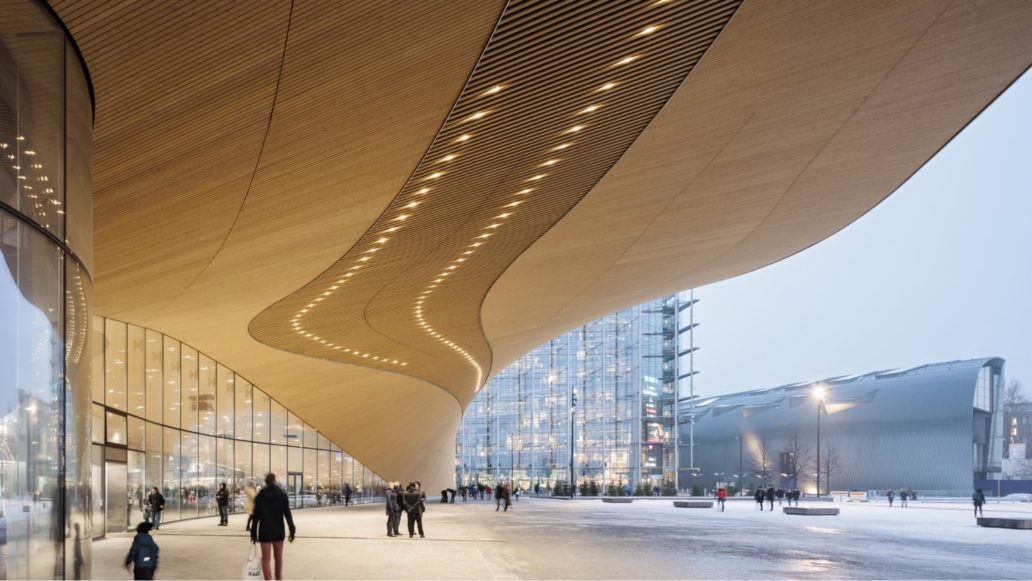 People walking in front of Helsinki Central Library, a big wooden building. 