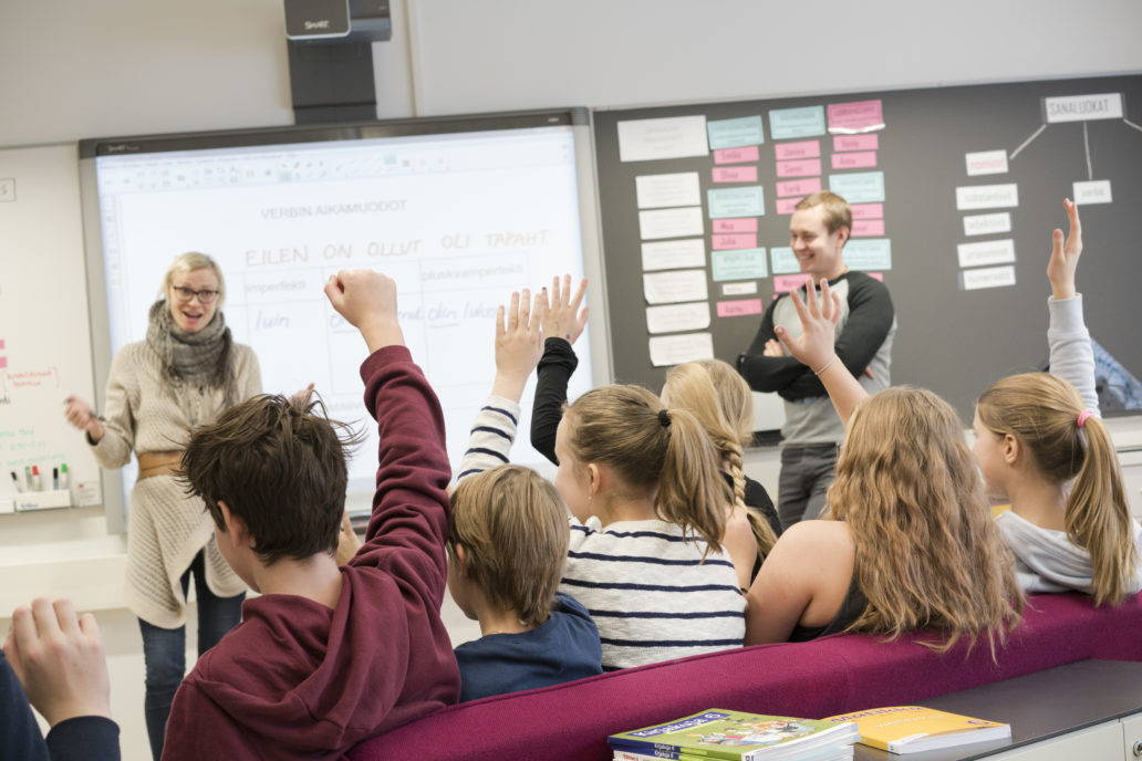 Children raising their hands at school.