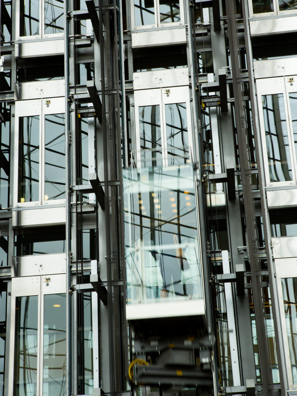 Elevators in a row and a person inside a moving elevator.