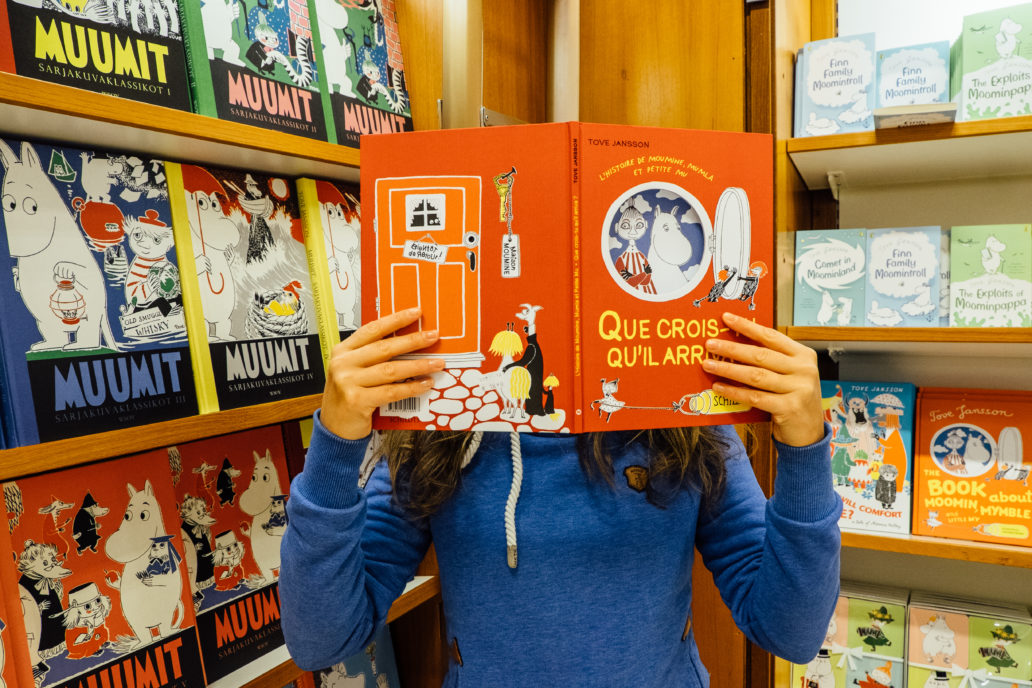 A person holding a Moomin book in a bookshop.