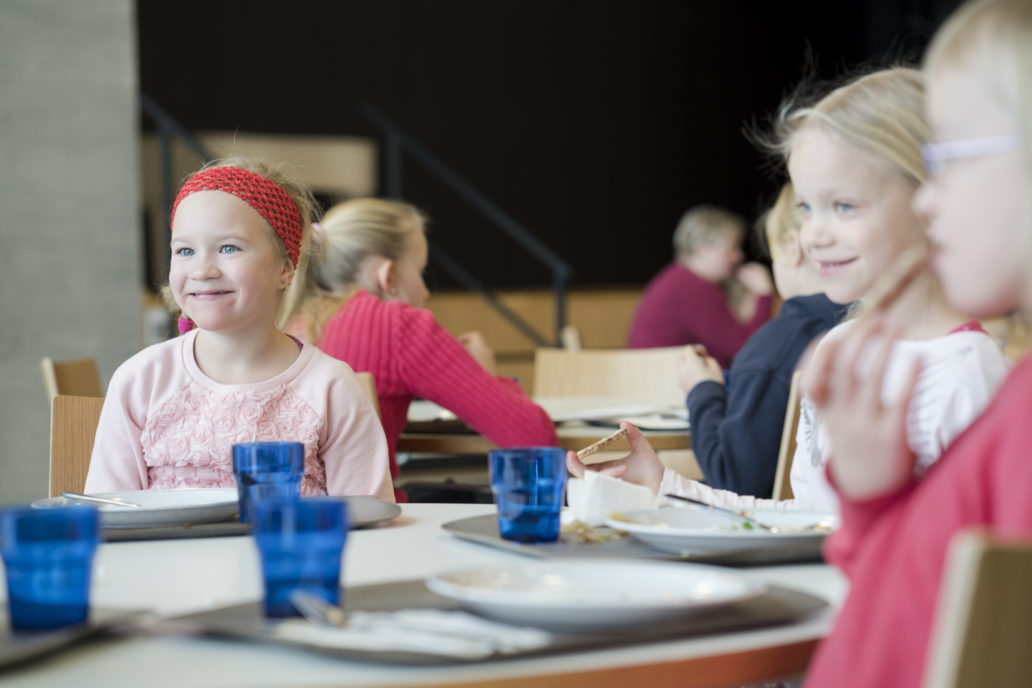 A group of children is eating and smiling. 