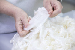 Hands stretching wool-like raw material for repurposing