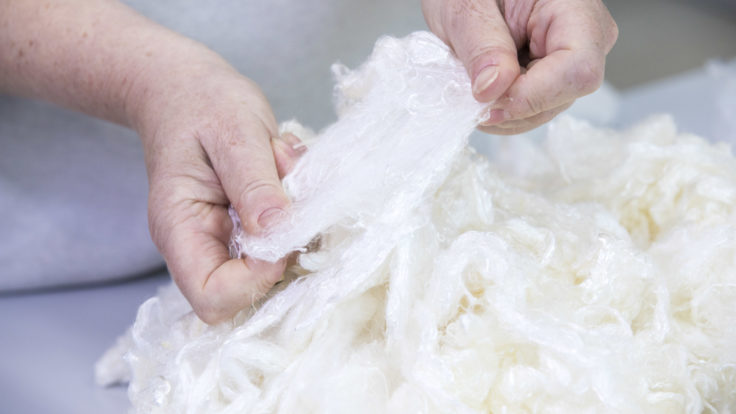 Hands stretching wool-like raw material for repurposing