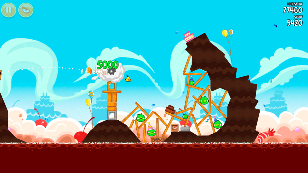 A scene from the Angry Birds game, a yellow bird flying into a wooden fort with green pigs. 