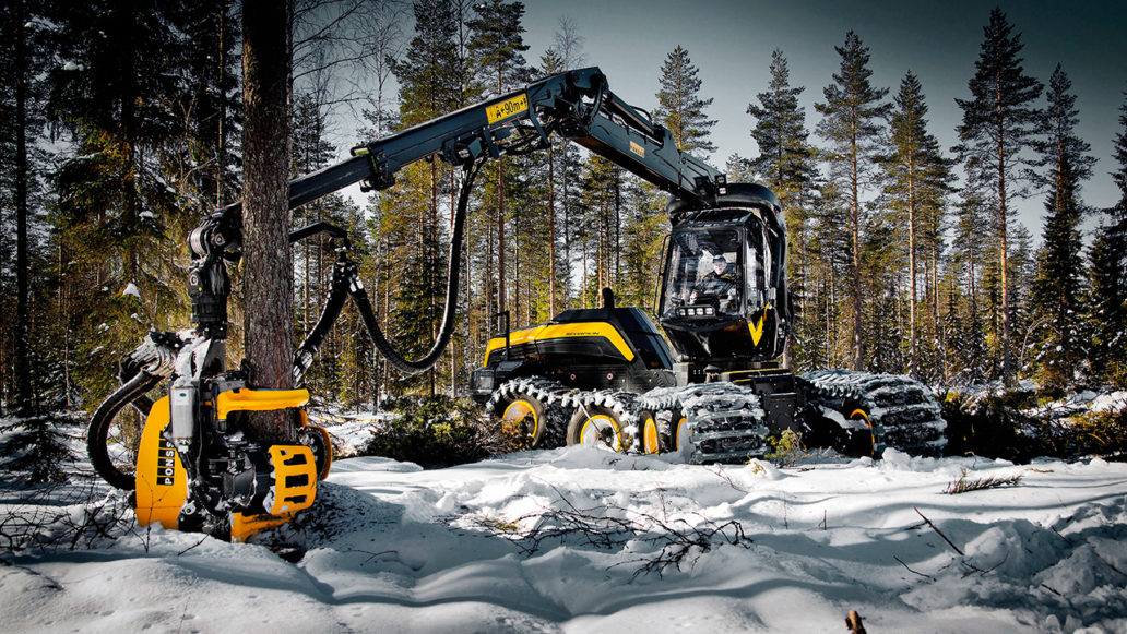 A big forestry machine at work in a snowy forest. 