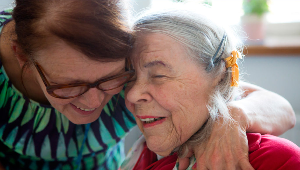 Two elderly women hugging.